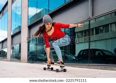 Cool skater woman practicing with her longboard in the city and having fun.
