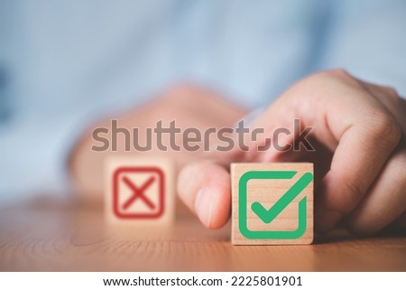 Businessman select green correct sign mark between Red Cross mark which print screen on wooden cube block for approve and reject business proposal concept.