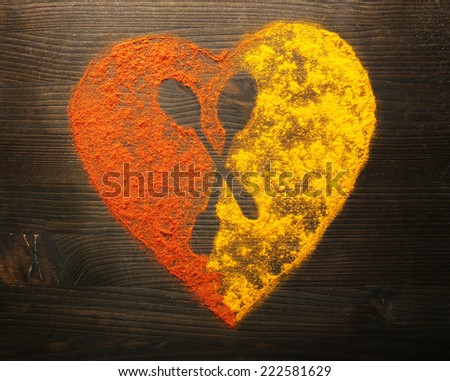 Spices on table in shape of heart with spoon silhouette, close-up 