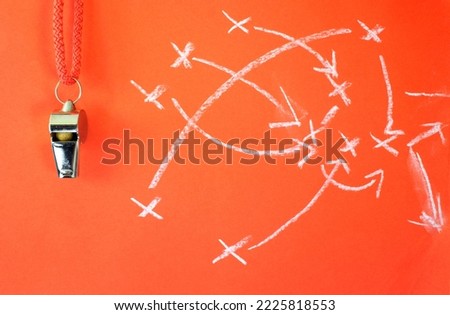 Whistle of soccer referee or trainer and soccer tactics scribble on red background. Great soccer event this year,close up Royalty-Free Stock Photo #2225818553