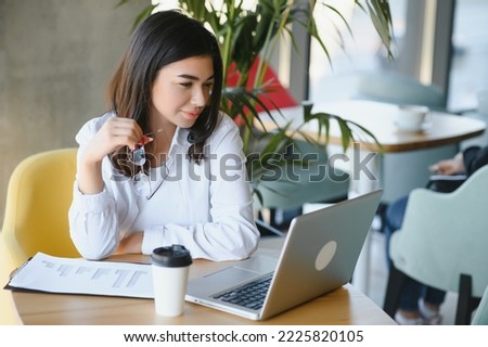 Smiling girl student study online with skype teacher, happy young woman learn language listen lecture watch webinar write notes look at laptop sit in cafe, distant education.
