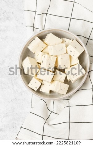 Tofu soy cheese or paneer or feta cheese cubes in a ceramic bowl on a checkered napkin isolated top view Royalty-Free Stock Photo #2225821109