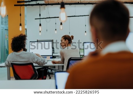 Two colleagues working on a project in modern startup offices. Guy with afro haircut and a female blonde employee working at the office.