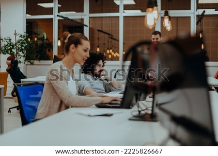 Two colleagues working on a project in modern startup offices. Guy with afro haircut and a female blonde employee working at the office.