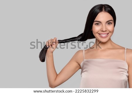 Portrait of beautiful young woman with healthy strong hair on light grey background, space for text