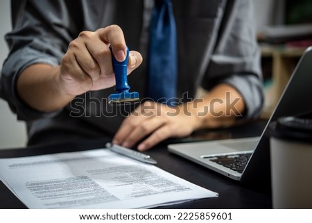 businessman hand stamping approved on certificate document contract in office. Lawyer stamping permit on paperwork at wooden desk.