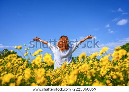 Happy young woman enjoying in yellow chrysanthemum field. Royalty-Free Stock Photo #2225860059
