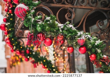 Building front decorated to Christmas with christmas trees fir branches, decorations and garland lights - festive and winter holidays concept