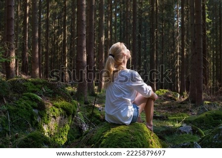 Woman sitting in green forest enjoys the silence and beauty of nature. Royalty-Free Stock Photo #2225879697