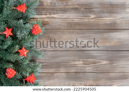 Christmas border. Fir branches and red festive decorations, stars and hearts on a wooden background. Happy new year. Copy space, top view, flat lay.
