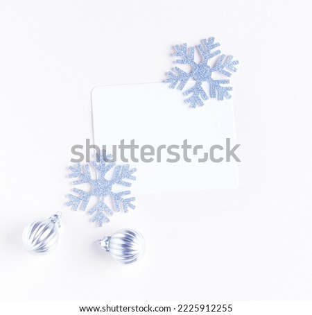 A white sheet of paper for congratulations surrounded by snowflakes and Christmas toys. christmas pink background. 
