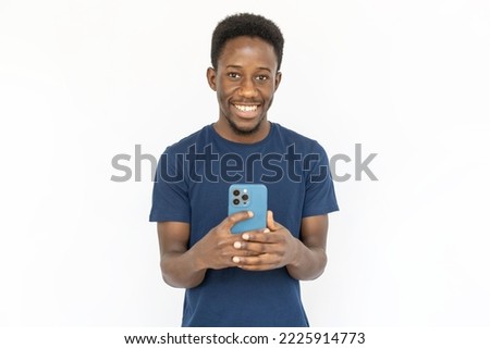 Happy man taking photo with smartphone. Young African American male model in blue T-shirt taking picture with phone and smiling. Portrait, studio shot, technology, photo concept