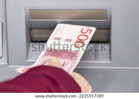 woman takes money out of an ATM, swedish 500 kronor, financial concept Royalty-Free Stock Photo #2225917389