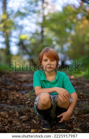 a boy of nine sits on a path in the woods alone