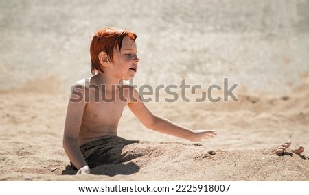 boy nine years old on the beach digs into the sand