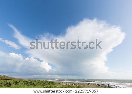 Big summer clouds rising above the ocean on a sunny day when bad weather is approaching the coast