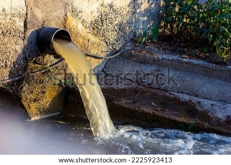 Wastewater sewage pipe dumps the dirty contaminated water into the river. Water pollution, environment contamination concept Royalty-Free Stock Photo #2225923413