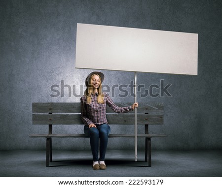 Young girl in casual with white banner sitting on bench. Place for text