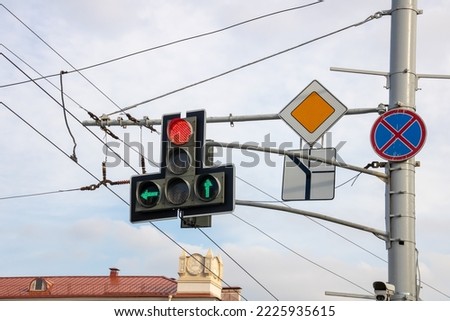 Traffic light with arrows and road signs on a pole