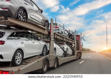 Transportation of new and very expensive cars. Hauling cars trailer and truck pulls rides on the highway Royalty-Free Stock Photo #2225940955