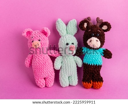 Amigurumi soft toys on a pink background with copy space. Soft Toy Day, holiday. card. Pig, bunny and bull amigurumi