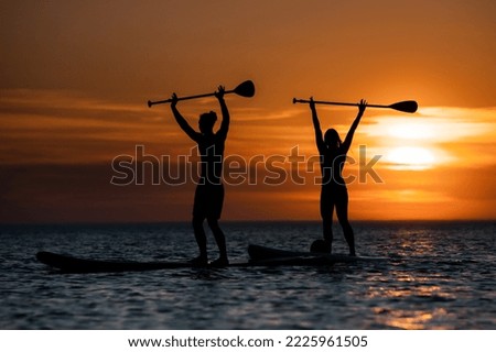 People and sunset with sups on baltic sea