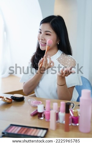 online trading business, a beautiful young woman working independently at home reviewing cosmetic products through the camera to customers to increase their interest in making a purchase decision.
