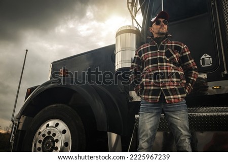 Caucasian Commercial Semi Truck Driver in His 40s in Front of a Vehicle. Ground Transportation Theme. Royalty-Free Stock Photo #2225967239