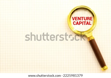 Economy and business concept. On a white background there are figures of businessmen and a magnifying glass, inside of which there is an inscription - Venture capital