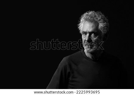 Black and white portrait of an attractive older Caucasian man with grey hair and beard. Turned to the right side with a serious or pensive expression.  Royalty-Free Stock Photo #2225993695