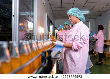 Beverage worker in drink factory stand working near drinking bottle conveyor production line