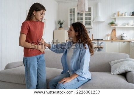Stomach pain in children. Unhealthy teenage girl child complaining of stomachache or bloating to mother. Loving caring mom helping teen daughter with menstrual pain, talking about first period Royalty-Free Stock Photo #2226001259