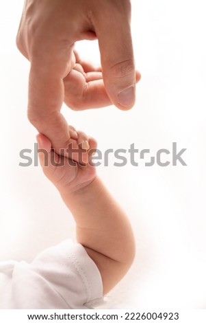 Close-up little hand of child and palm of mother and father. The newborn baby has a firm grip on the parent's finger after birth. A newborn holds on to mom's, dad's finger.  Royalty-Free Stock Photo #2226004923