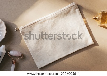 Blank canvas makeup bag mockup on a beige, cream background. Natural sunlight Royalty-Free Stock Photo #2226005611