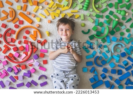 Wooden bricks Montessori material rainbow spectrum. Little cute boy plays with cubes. Top view.  Royalty-Free Stock Photo #2226013453