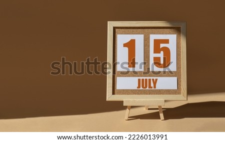 July 15th. Day 15 of month, Calendar date. Cork board, easel in sunlight on desktop. Close-up, brown background.  Summer month, day of year concept.