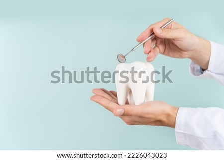 Dentist hand with healthy white tooth model and dentist mirror on a blue background. Copy space. Teeth care, dental treatment, tooth extraction, implant concept. Dental clinic special offer Royalty-Free Stock Photo #2226043023
