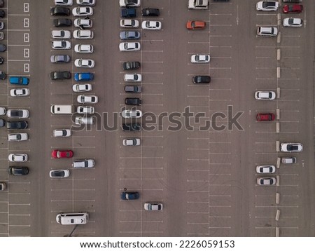 Aerial view full cars at large outdoor parking lots. Outlet mall parking congestion and crowded parking lot, other cars try getting in and out, finding parking space.