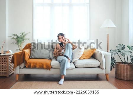 Happy asian woman listening to music from mobile phone while sitting on the the sofa at homes, Smiling girl relaxing with headphones in morning, Time to relax. copy space. Royalty-Free Stock Photo #2226059155