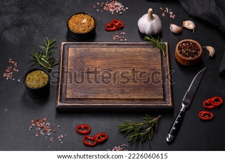 Ingredients for cooking at home: pepper, salt, rosemary, spices and herbs on a dark concrete background