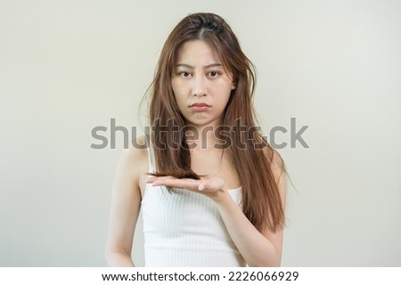 Damaged Hair, frustrated asian young woman, girl hand in holding splitting ends, messy unbrushed dry hair with face shock, long disheveled hair, health care of beauty. Portrait isolated on background. Royalty-Free Stock Photo #2226066929