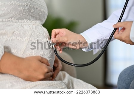 close-up image, Female doctor using a stethoscope to listen to the baby's heartbeat in a pregnant woman's belly. motherhood and Antenatal care concept