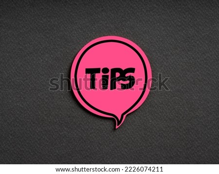 The word tips on pink speech bubble on black background. Information suggestion, advice or guidance concept.