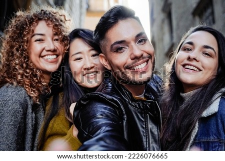 Diverse group of friends having fun taking selfie outdoor during winter time - Focus on gay transgender man wearing makeup