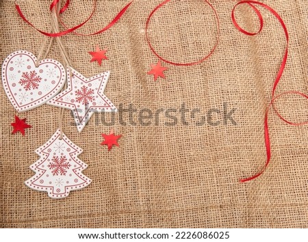 Red - white Wooden Christmas decorations with tinsel on a background of burlap with artificial snow
