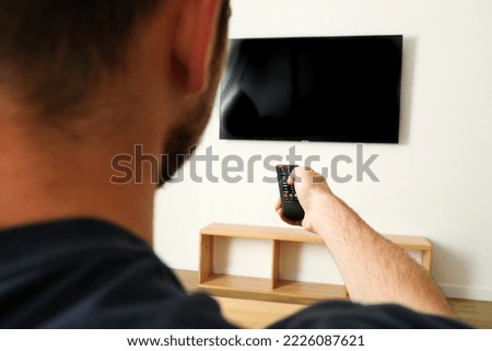 Young man pressing the TV remote, close up