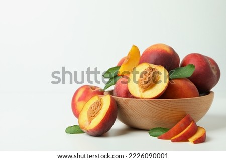 Wooden bowl with peach fruits on white table Royalty-Free Stock Photo #2226090001