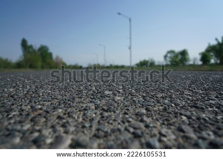 Country asphalt road. Symmetrical beautiful row of street lights placed on both sides of street with forest trees. Street road leads to horizon, sunny day in modern fresh looking city. low angle view Royalty-Free Stock Photo #2226105531