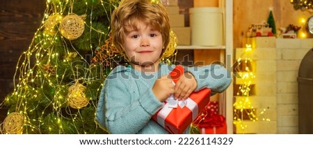 Winter Christmas children. Child with gift. Child with a Christmas present on wooden house background.
