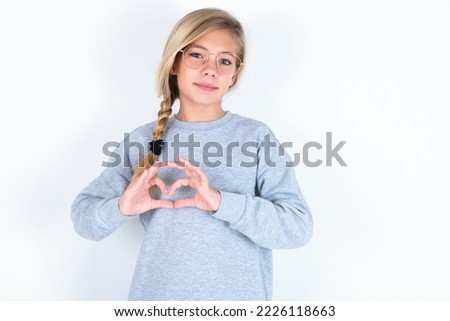 Serious caucasian teen girl wearing gray sweater over white background keeps hands crossed stands in thoughtful pose concentrated somewhere